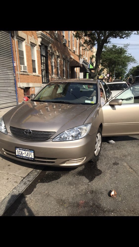A tan sedan with the front door open and someone exiting the vehicle